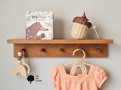 there is a wooden shelf with some clothes on it and a book next to it