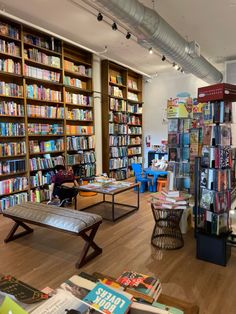 a room filled with lots of books on shelves next to tables and chairs in front of them