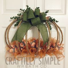 a wreath is hanging on the front door with green ribbon and orange flowers in it