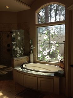 a bath tub sitting under a window next to a sink and shower stall in a bathroom