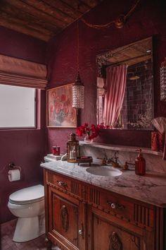 a bathroom with purple walls and marble counter tops, along with a white toilet in the corner