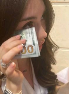 a woman is holding money up to her face