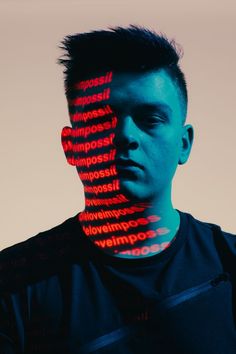 a man's face is covered with words in red and blue light, while the image appears to be distorted