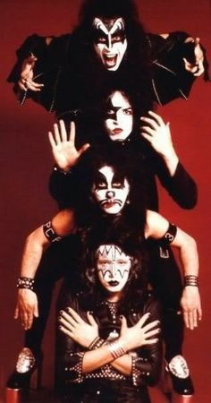 the kiss band posing for a photo in front of a red background with their arms around each other