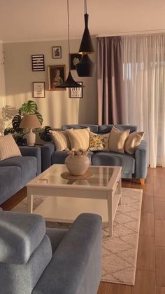 a living room filled with blue couches next to a white coffee table in front of a window