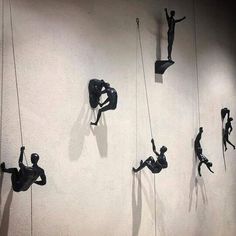 several sculptures are hanging on the wall and one person is climbing up to the ceiling