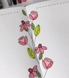 an open book with flowers on it and crayon markers in the bottom corner