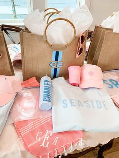 the table is covered with pink and blue items, such as hats, sunglasses, t - shirts, and beach towels