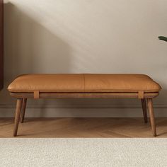 a wooden bench sitting next to a potted plant on top of a hard wood floor