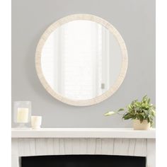 a white fireplace with a mirror above it