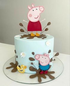 a peppa pig cake on top of a blue frosted cake