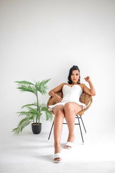 a woman sitting in a chair next to a potted plant and posing for the camera