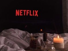 a table topped with candles and jars next to a wall that says netflix on it