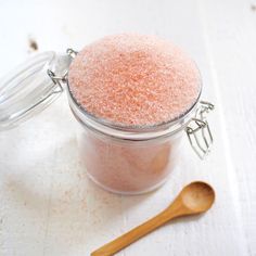 a small jar filled with pink sugar next to a wooden spoon