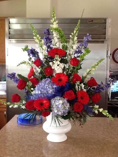 a vase filled with red, white and blue flowers sitting on top of a counter