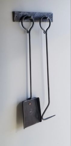 a wall mounted device with two hooks attached to it's sides and a square piece of metal hanging from the side