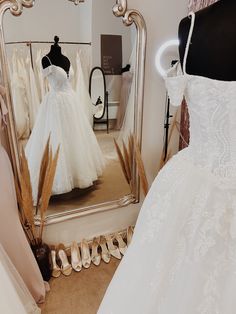 a wedding dress is on display in front of a mirror and other bridal gowns