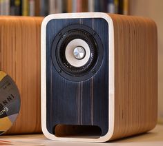 a speaker sitting on top of a wooden table next to a cd player and book