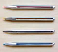 three pens sitting next to each other on top of a wooden table