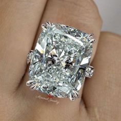 a close up of a person's hand holding a diamond ring