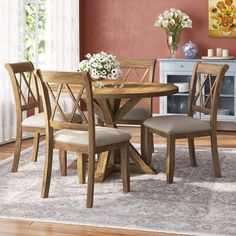 a dining room table with chairs and a rug on the floor