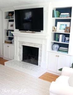 a living room with white furniture and a flat screen tv mounted on the fireplace mantel