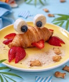 a croissant with strawberries and bananas on it is sitting on a plate