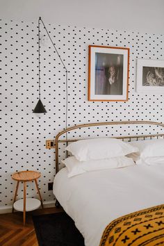 a bedroom with polka dot wallpaper and a bed in the foreground, two pictures on the wall