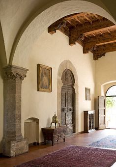 an arched doorway leads into a large room with columns and rugs on the floor