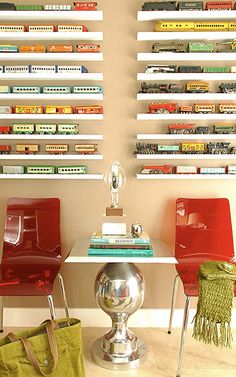 two red chairs sitting next to each other in front of a wall filled with books