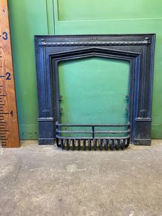 a black fireplace with a ruler next to it and a green wall in the background