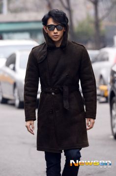 a man walking down the street wearing a brown coat