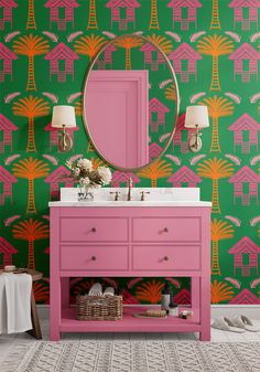 a bathroom with pink vanity, green wallpaper and gold mirror on the sideboard