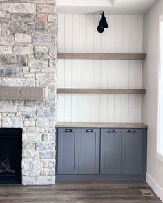 an empty living room with stone fireplace and built - in shelving