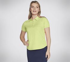 a woman wearing a lime green shirt and navy blue skirt with her hands on her hips