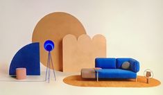 a blue couch sitting on top of a rug next to a table and lamp in front of a white wall