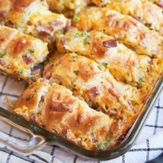 a casserole dish with ham and cheese in it sitting on a tablecloth