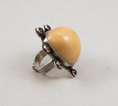 The Tagua Dome Carnelian Ring is a statement ring featuring a large tagua nut dome. The tagua nut has been used in Japanese sculpture and jewelry for centuries. The Tagua Dome is set in a silver bezel and surrounded by a halo of carnelian cabochons. Rounded square ring band, Size 9. Please check the size carefully. This is a one-of-a-kind piece of art jewelry and cannot be resized. Gold Dome Cabochon Ring In 14k Gold, Luxury Domed Cabochon Dome Ring, Gold Cabochon Dome Ring, Polished Modernist Dome Ring, Japanese Sculpture, Croatian Tattoo, Tagua Nut Jewelry, Tagua Nuts, Rounded Square