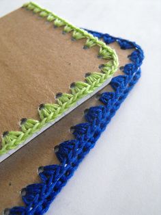 two notebooks with blue and green crocheted edges on top of each other