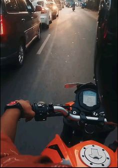 a person riding a motorcycle down a street next to parked cars