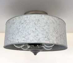 a light fixture with a white shade hanging from it's center point on the ceiling