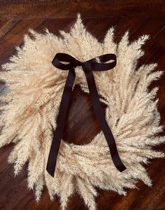 a white wreath with black ribbon on top of a wooden floor