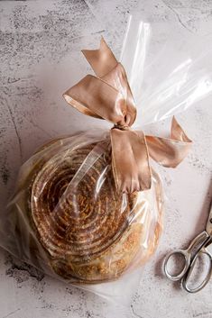 a bagel wrapped in plastic and sitting next to scissors