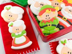 decorated cookies in the shape of santa and mrs claus are sitting on red napkins