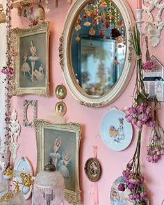 a pink wall with pictures and mirrors on it