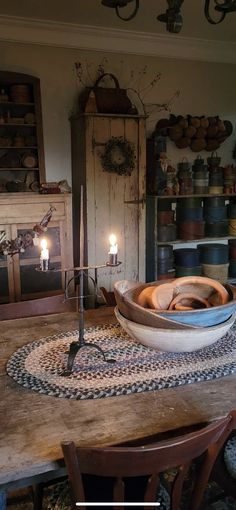 a wooden table topped with a bowl filled with lots of bowls next to a candle