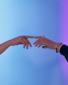 two people reaching out their hands to touch each other's fingers against a purple and blue background