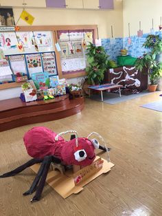 a large spider sitting on top of a cardboard box in a room with wooden floors