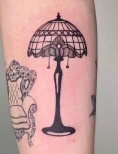 a tattoo on the arm of a person with a lamp and chair in front of it