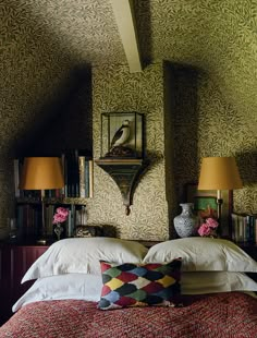 there is a bed with two pillows on it in the room that has green wallpaper